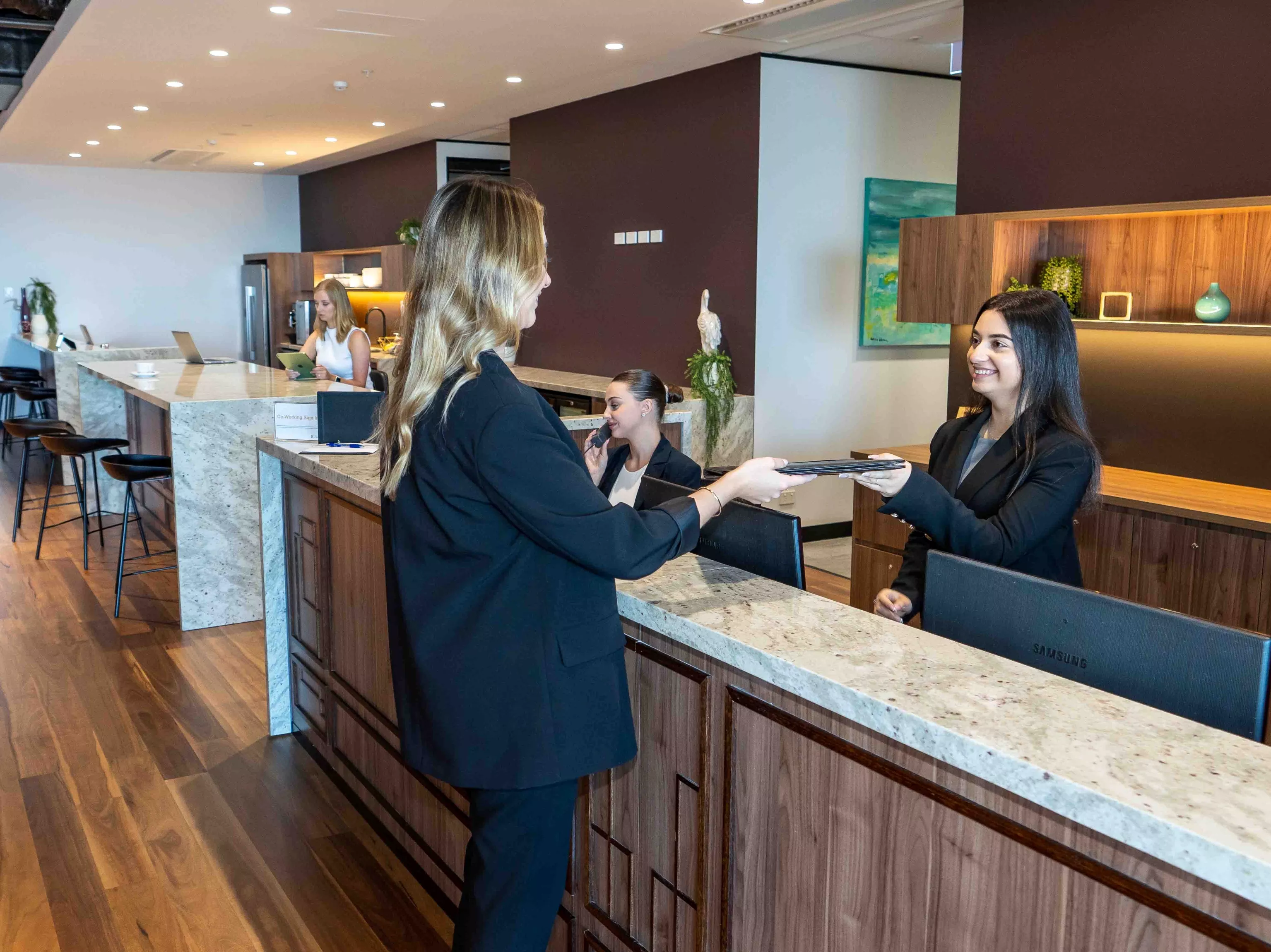 A dedicated receptionist helping a client in the modern co-working space of in Servcorp 100 Mount Street