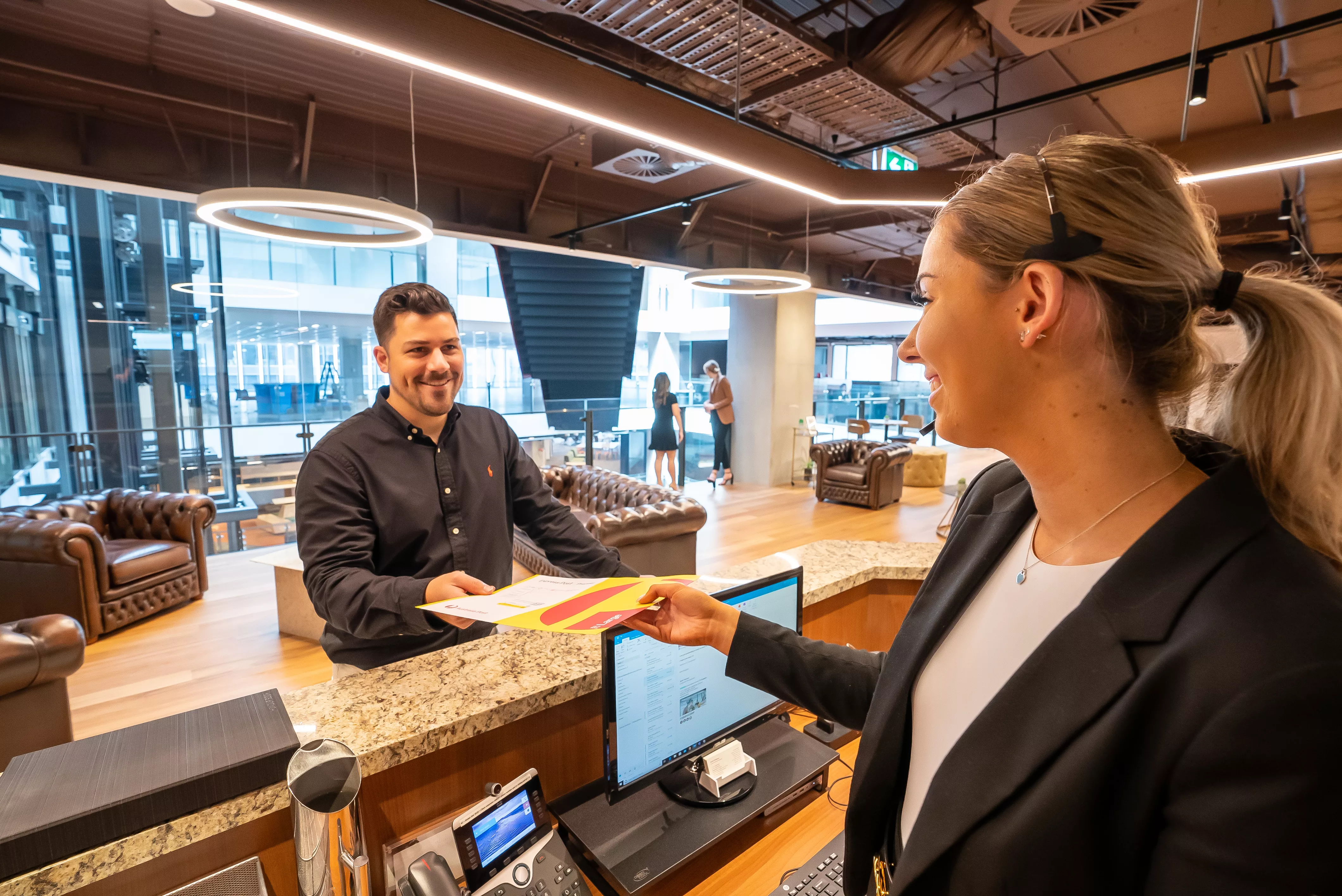 Dedicated receptionist issuing a parcel to a client in 140 St Georges Terrace Perth
