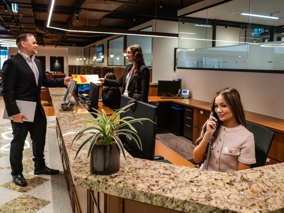 A dedicated receptionist on the phone and another with a client in the modern co-working space of in Servcorp 3 Parramatta Square