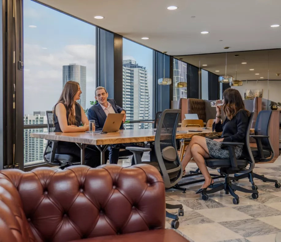 Close up on clients working in a long table in a modern coworking space with impressive views in Servcorp 140 William, Melbourne