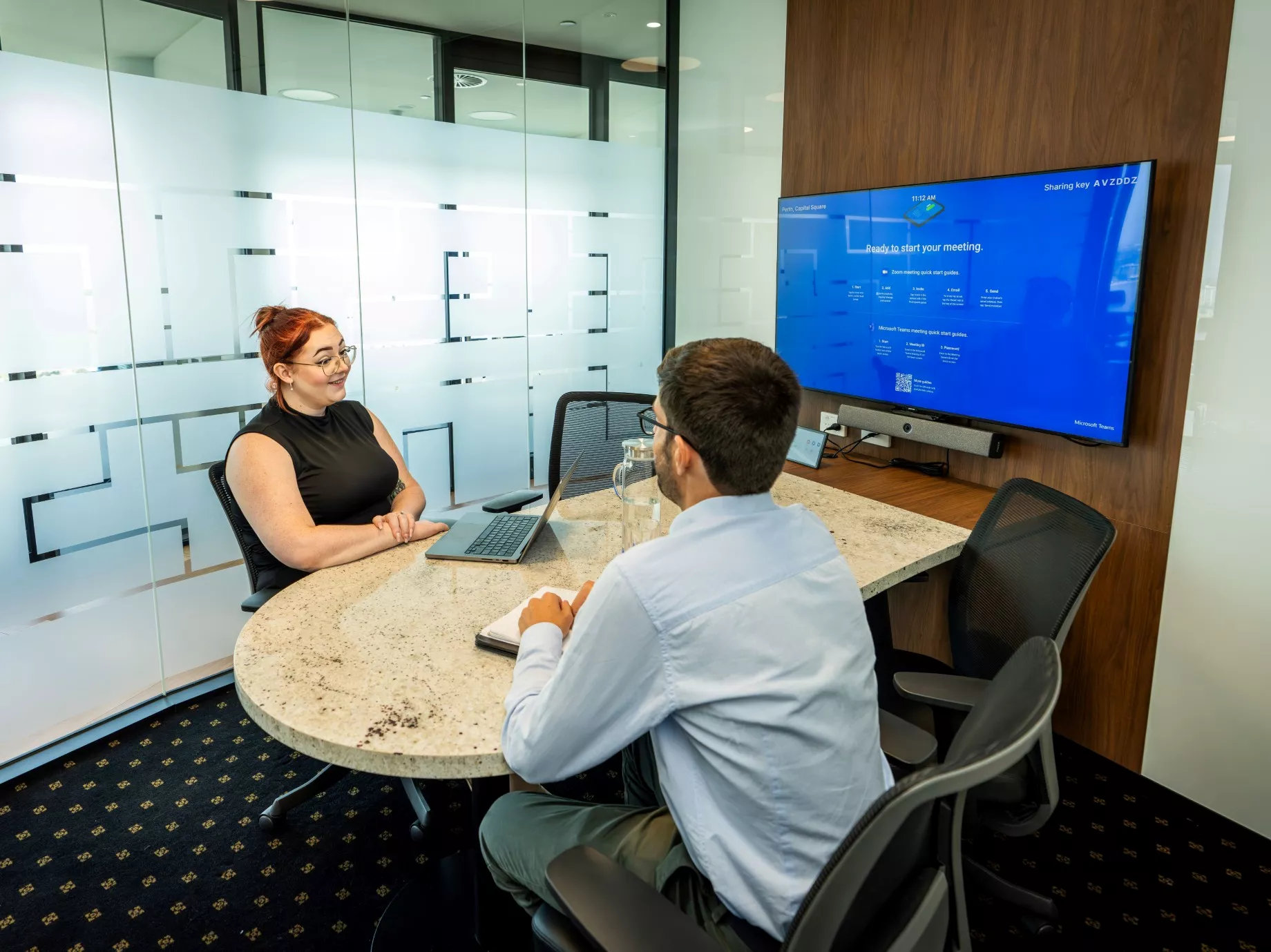 A client talking to her clients in a modern meeting room space using the projection and screen in Servcorp Capital Square Tower 3 Perth